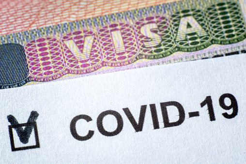 COVID-19 coronavirus pandemic and travel concept, document with COVID positive test and Visa stamp in passport. Border control and quarantine of tourists. Novel corona virus outbreak in the World.