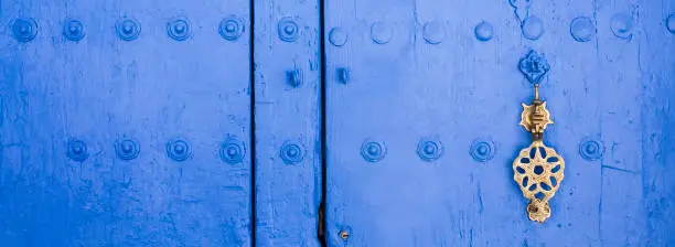Background of traditional powder blue painted door with golde doorknocker. Chefchaouen, Morocco