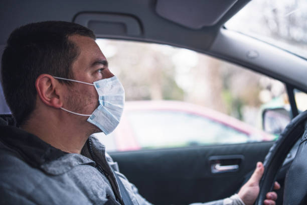 istock Man With Protective Face Mask Driving The Car 1212614792