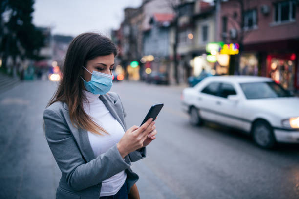 istock Woman With Protective Face Mask Using Smart Phone. 1212614798
