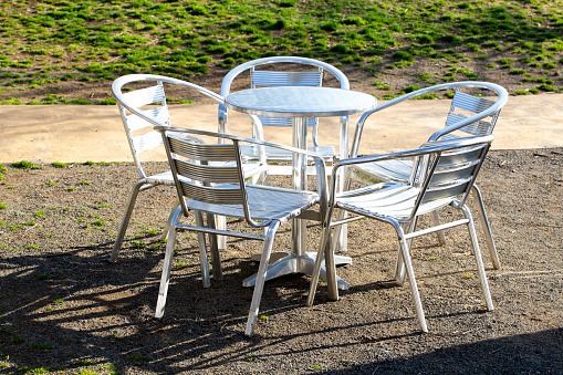 Four wire chairs with heart shaped backs around a glass topped table in a Cape Cod patio.