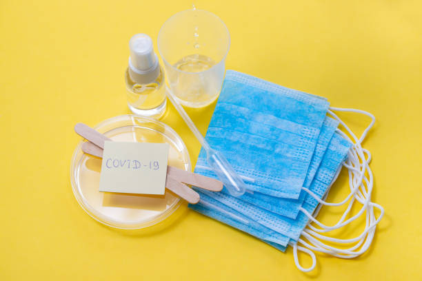 istock medical mask, plastic cups and other objects in yellow background 1212617022