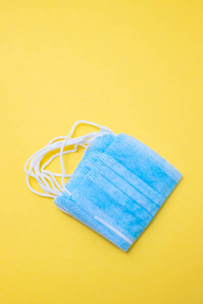 istock blue protective masks on yellow paper background. 1212617658