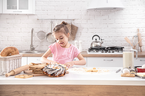 A cute little girl is cooking homemade cakes in the kitchen. Children's development and family values.Healthy diet.