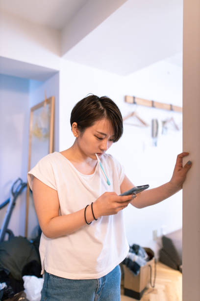 istock Young woman using smart phone during brushing teeth in the morning 1212619692