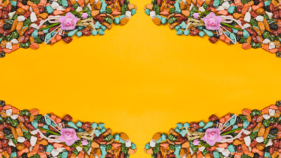 Festive decoration. candy pebbles on a yellow background. sweets in the form of colored stones. symmetrical frame made from colorful candies