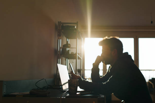 Young freelancer working from home in the morning while having coffee.  Small business owner working in home office by himself alone at home. stock photo