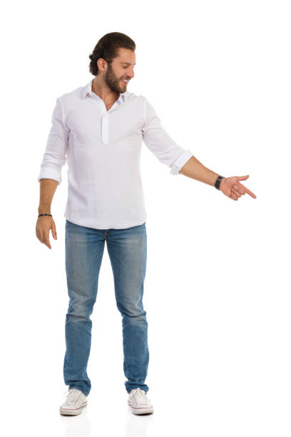 istock Smiling Handsome Young Man Is Standing Looking Away And Pointing Down 1212623141