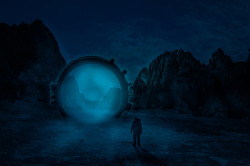 Man standing in front of dimensional gate. Futuristic landscape at night. Mountains at background.
