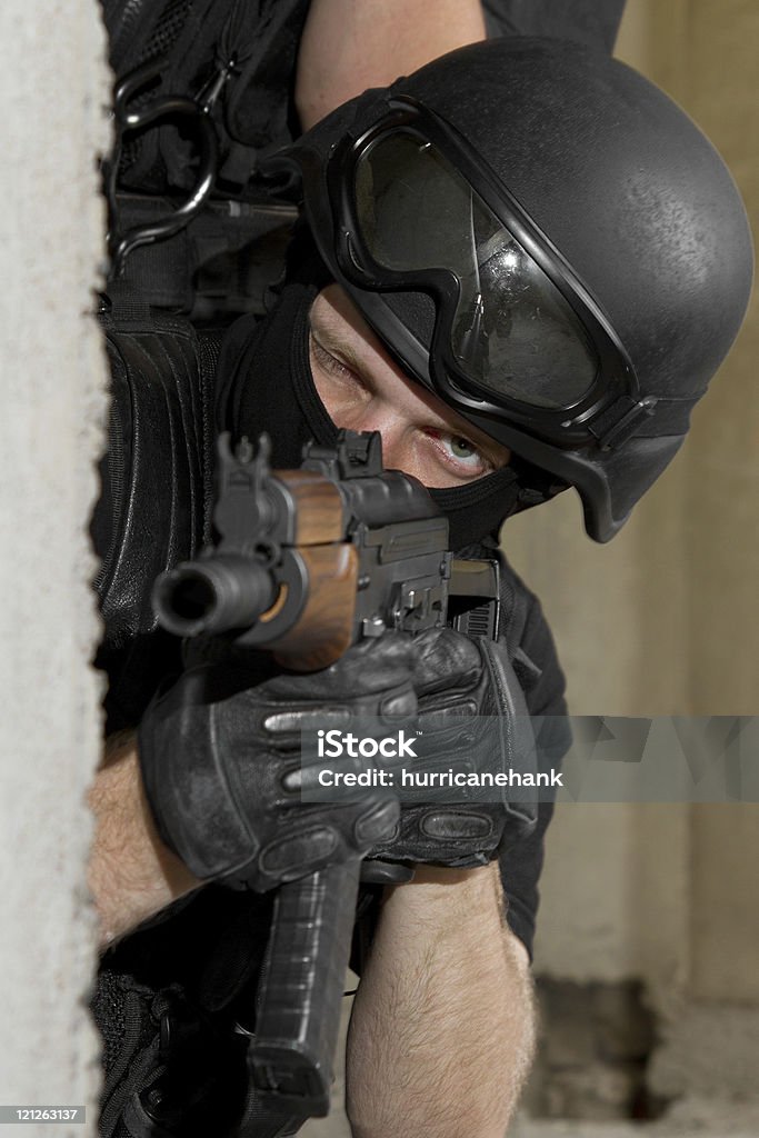 Soldier in black mask targeting with AK-47 rifle from cover Photo of armed man in combat uniform playing terrorist or special forces team member AK-47 Stock Photo