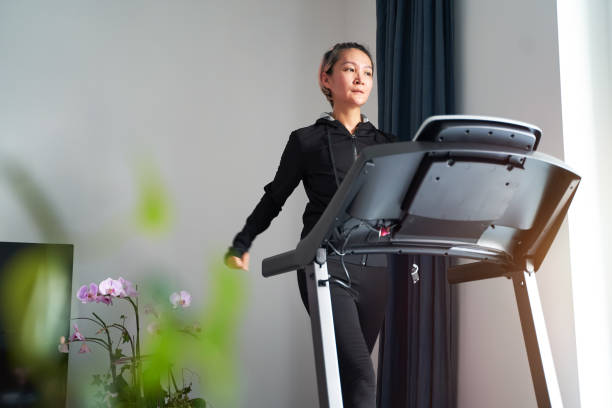 Asian woman exercising on treadmill home gym stock photo