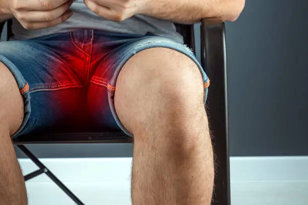 The man spread his legs, close-up Pain in the groin. Men's problems, acute pain, inconvenience