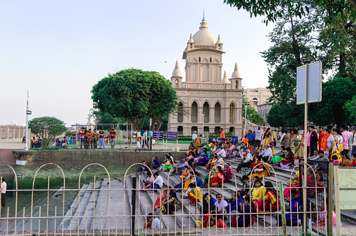 Large group of tourists people sitting on the steps and staircases that lies on the west bank of Hooghly River. Belu Mah Ramakrishna Swami Vivekananda Mission. Kolkata India South Asia March 2020