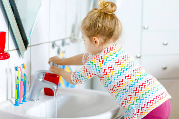 carina bambina che si lava le mani con acqua e sapone in bagno. adorabile bambino che impara a pulire le parti del corpo. azione di routine igienica durante la malattia virale. bambino a casa o all'asilo nido. - home interior sparse bedroom inside of foto e immagini stock