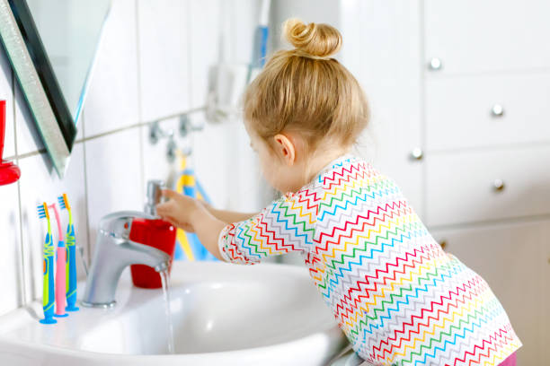 carina bambina che si lava le mani con acqua e sapone in bagno. adorabile bambino che impara a pulire le parti del corpo. azione di routine igienica durante la malattia virale. bambino a casa o all'asilo nido. - home interior sparse bedroom inside of foto e immagini stock