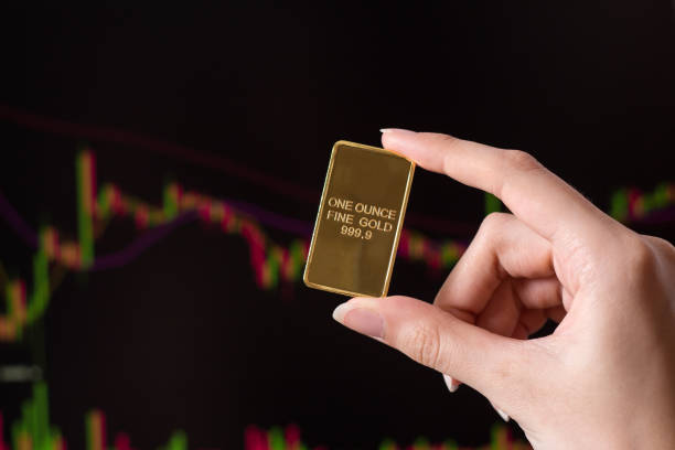 The hand holds a gold bar on the background of a laptop on which there is a trading price chart. One ounce of gold in hand. Trading gold on the stock exchange and Forex. The hand holds a gold bar on the background of a laptop on which there is a trading price chart. One ounce of gold in hand. Trading gold on the stock exchange and Forex. ounce stock pictures, royalty-free photos & images