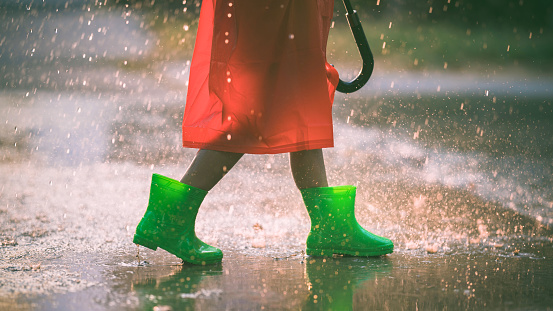 Asian girl is wearing green boot. She is in the rain.
