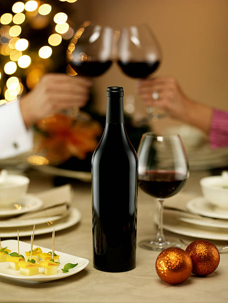 A bottle of wine and a red heart on a shiny yellow bright bokeh background . Congratulations on a holiday or Valentine's Day