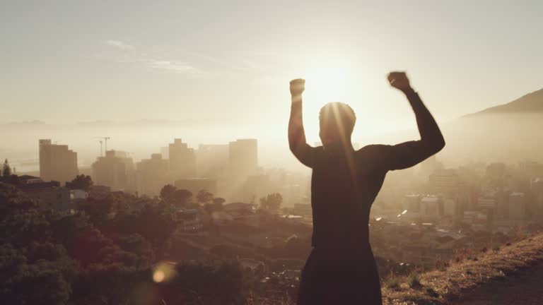 4k video footage of a young man celebrating an accomplishment while jogging on a mountain against an urban background
