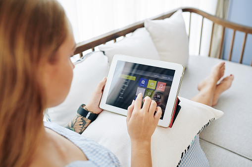 Young woman choosing application to use on her tablet computer when resting at home