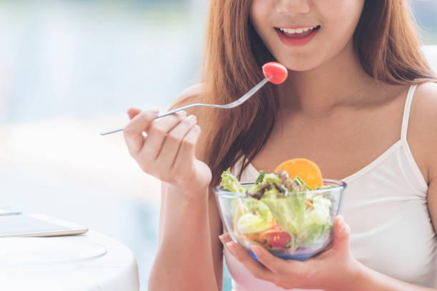 comida saludable estilo de vida saludable con joven mujer feliz comiendo ingredientes frescos verdes ensalada orgánica. chica vegana sosteniendo ensaladera con la cara sonriente comiendo alimentos saludables para la dieta. - women food smiling serving size fotografías e imágenes de stock