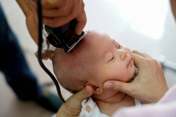 Baby one months old is shaved the hair in barber shop. Thai traditional must do shaving the first hair from birth to remove cradle cap from baby scalp. Hand holding baby head with so many cradle caps. bebé de un mes de edad se afianzó el pelo en la peluquería. thai tradicional debe afeitarse el primer cabello desde el nacimiento para eliminar la cuna del cuero cabelludo del bebé. mano sosteniendo la cabeza del bebé con tantas tapas de la cuna.