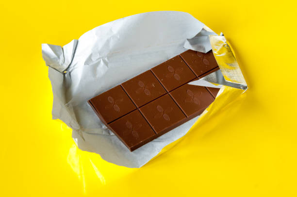 istock Milk chocolate bar in silver foil on a yellow background 1212664817