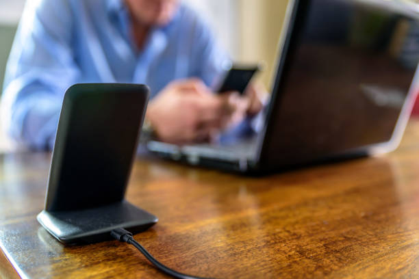 istock wireless phone charging stand over man holding smartphone at home office 1212669905
