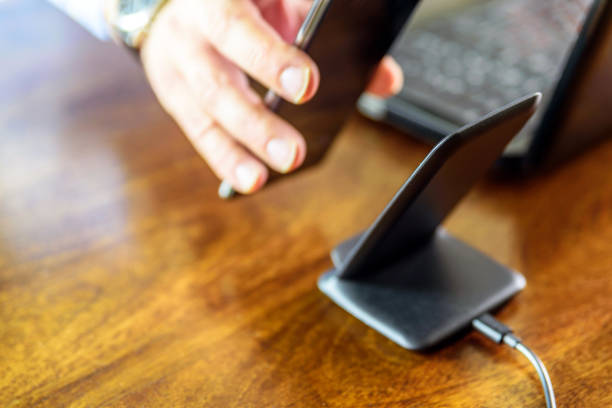 istock man charging smartphone using Wireless charging stand at home office 1212670903