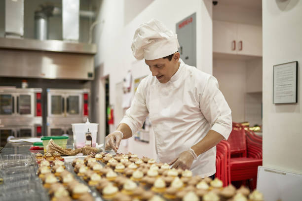 istock Mature Male Chef Decorating Iced Cupcakes in Vegan Bakery 1212674701