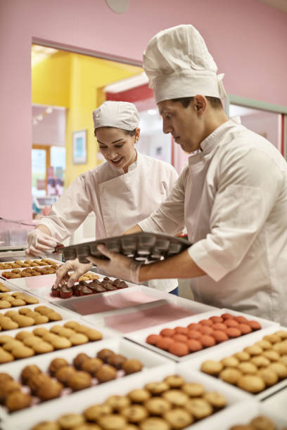 istock Male and Female Chefs Preparing Vegan Cupcakes for Icing 1212674784