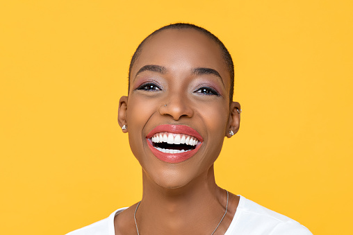Close up portrait of friendly happy African American woman smiling on isolated colorful yellow background