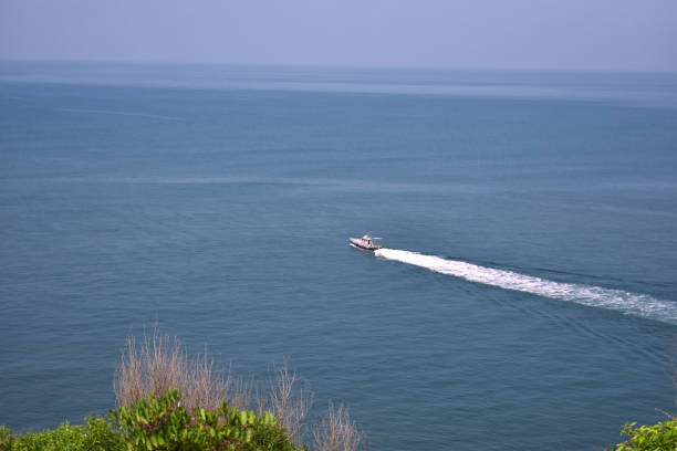 a speed boat moving forward leaving a white trail behind, far in the ocean a speed boat moving forward leaving a white trail behind, far in the ocean chapora fort stock pictures, royalty-free photos & images
