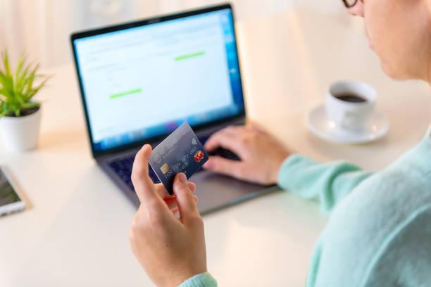 istock Holding a blue credit card and typing on a laptop 1212677468