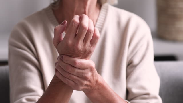 Senior grandmother massaging hand suffering from rheumatoid arthritis