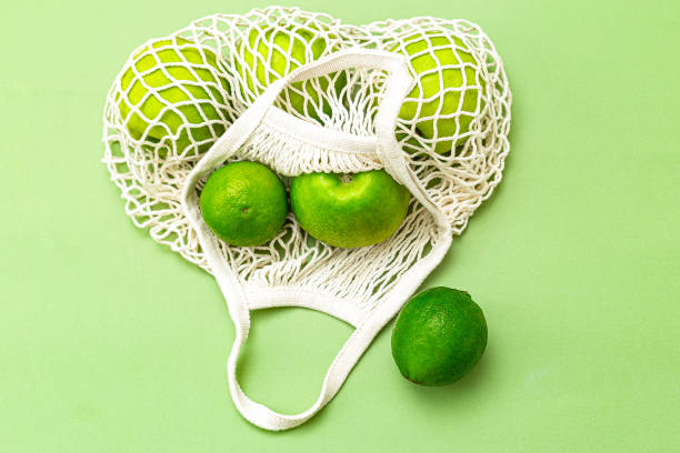 istock Net bag with green fruits on a green background. Reusable. Zero waste. Monochrome 1212680773