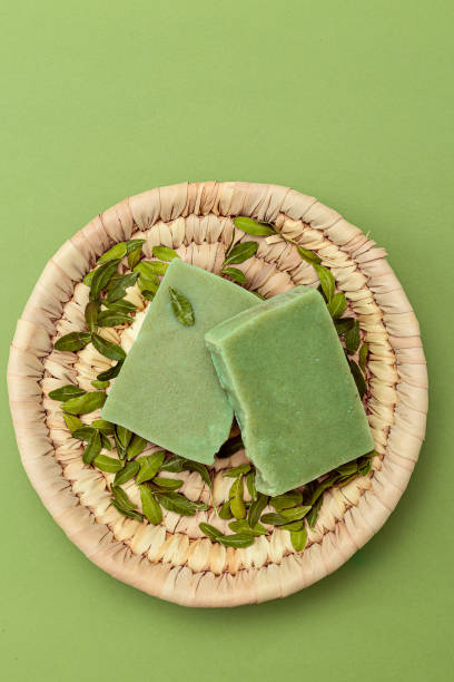 Natural green soap and eucalyptus leaves on a straw plate. Vertical format. Organic