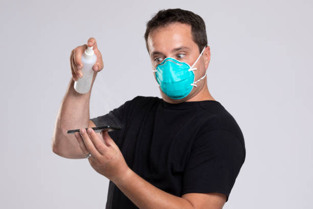 istock Man disinfecting his mobile phone. 1212683504