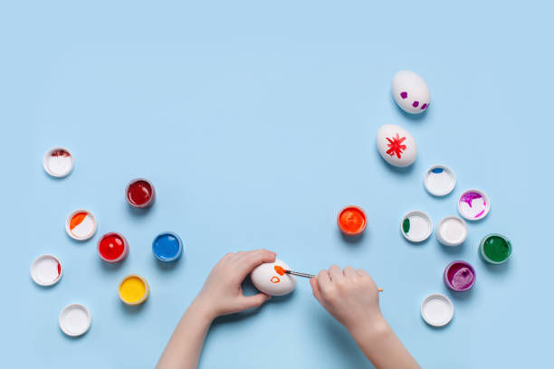 istock A child paints a white egg. Top view, place for your text 1212685211