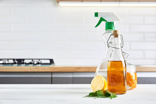 Eco-friendly natural cleaners: baking soda, soap, vinegar, salt, coffee, lemon and brush on a wooden table. Kitchen background.