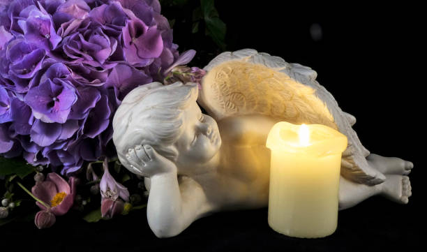 istock Angel and white candle on dark background 1212688644