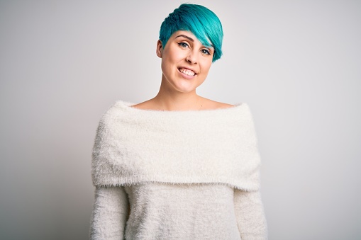 Young beautiful woman with blue fashion hair wearing casual sweater over white background with a happy and cool smile on face. Lucky person.