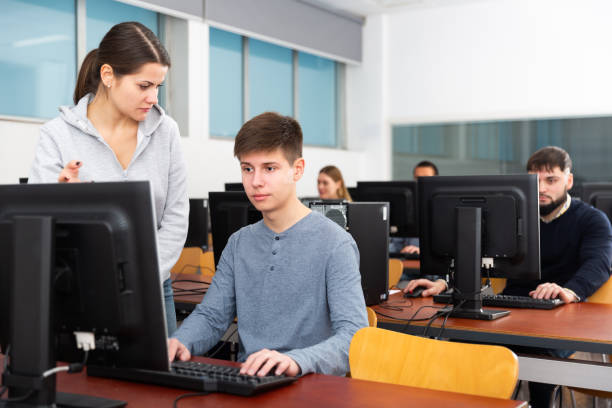 istock Female teacher helping young male student 1212690236