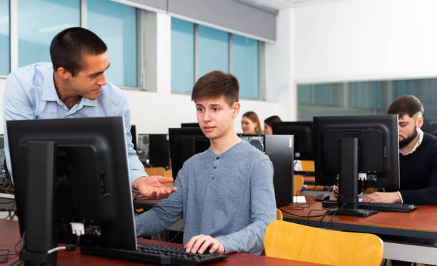 istock Teacher helping young male student 1212690257