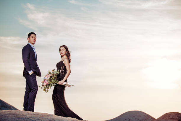 una sesión de retrato preboda de pareja china asiática en la duna de arena melaka durante la puesta del sol con el cielo dramático - face to face twilight togetherness vertical fotografías e imágenes de stock