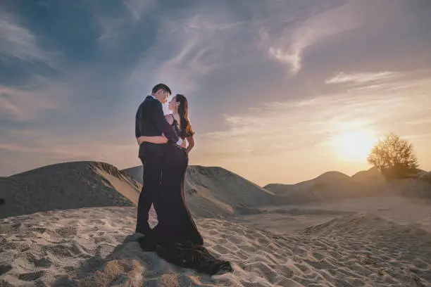 an asian chinese couple prewedding portrait session in melaka sand dune during sunset with dramatic sky