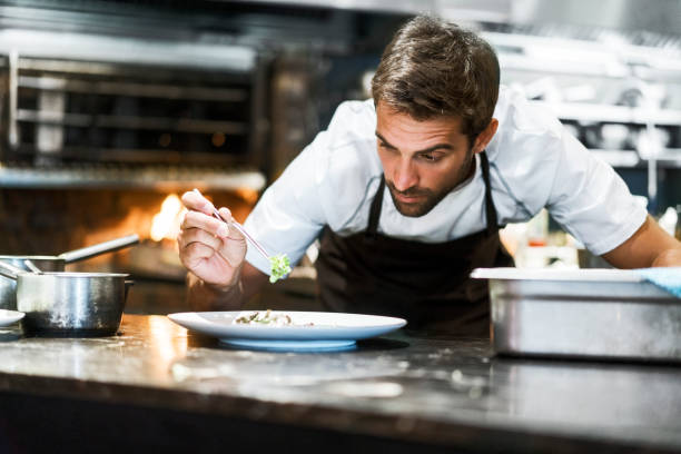 istock Male chef garnishing food in kitchen 1212690830