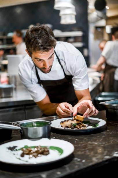 cuoco maschio prepara cibo in cucina commerciale - chef foto e immagini stock