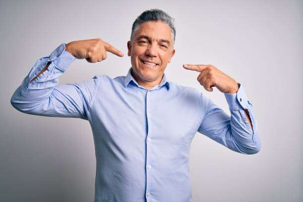 istock Middle age handsome grey-haired business man wearing elegant shirt over white background smiling cheerful showing and pointing with fingers teeth and mouth. Dental health concept. 1212691241