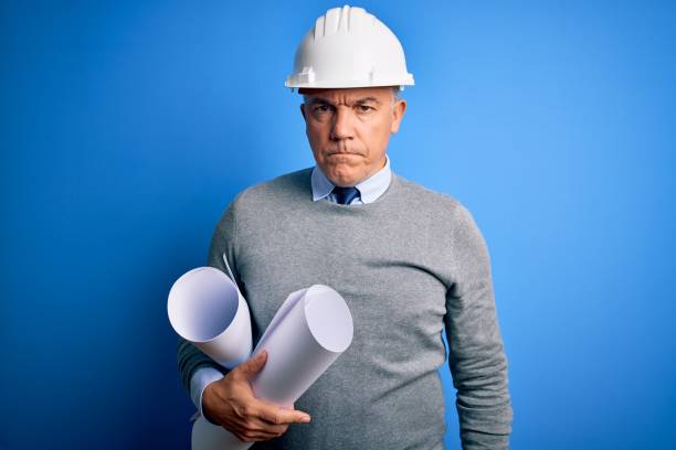 istock Middle age handsome grey-haired architect man wearing safety helmet holding blueprints skeptic and nervous, frowning upset because of problem. Negative person. 1212692497